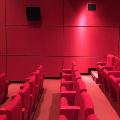 Ein leerer Kinosaal mit roten Kinosesseln, roter Wand und rotem Teppich.