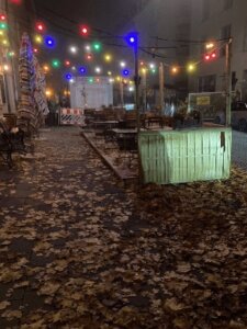 Ein leerer Schanigarten bei Nacht. Eine bunte Lichterkette leuchtet, die Szene sieht trostlos aus.