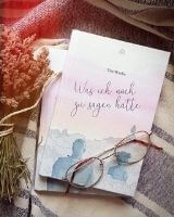 Ein Buch mit dem Titel "Was ich noch zu sagen hätte" liegt auf einer Decke, darauf eine Brille.